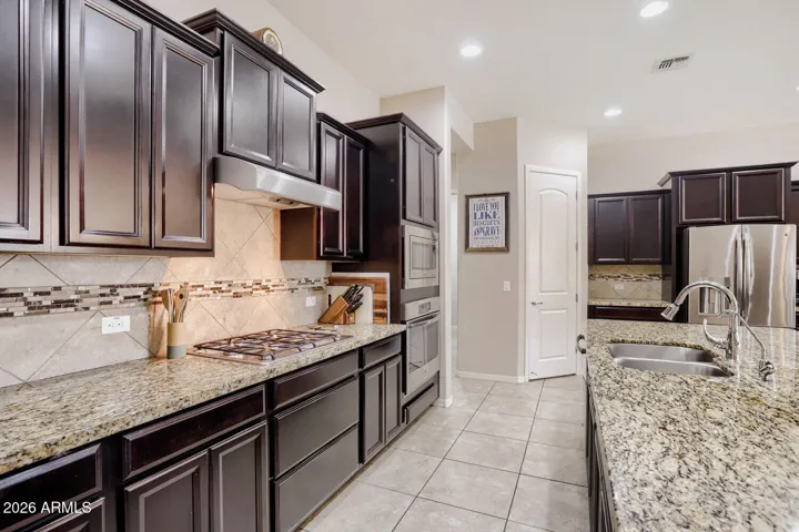 Designed for function and flow, the kitchen includes a gas cooktop, wall oven, and walk in pantry.