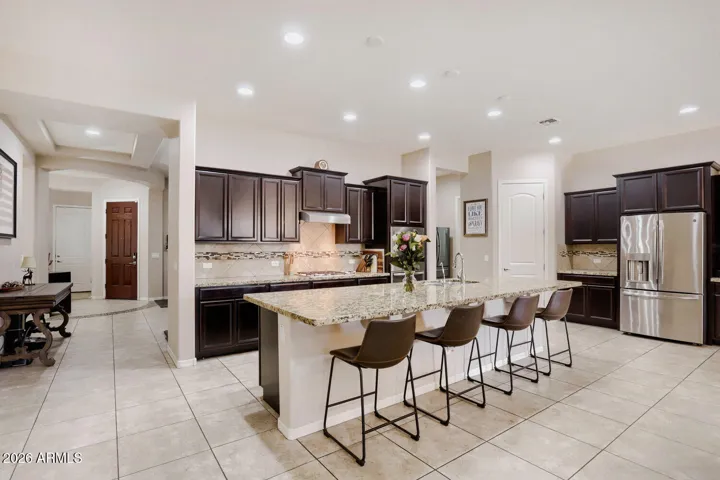 Kitchen features dark maple cabinetry, granite counters, breakfast bar seating, and generous prep space.