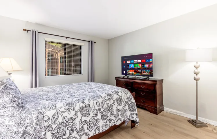 "Another view of your restful retreat — dresser storage, smart TV, and natural light through garden-view windows."
