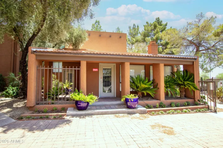 "The community clubhouse — beautifully landscaped Southwest exterior with covered entry, lush greenery, and welcoming curb appeal."