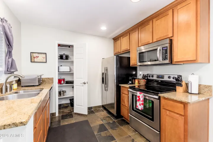 "Granite countertops, stainless steel appliances, and a dedicated pantry stocked with small appliances — this kitchen means business."