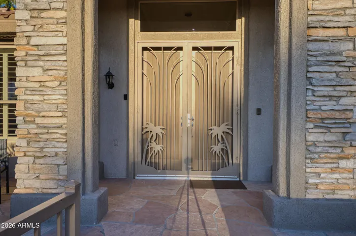 Enter from the walkway through the gated courtyard. Attractive stone adorns the front of the home, along with double front doors and custom security doors.