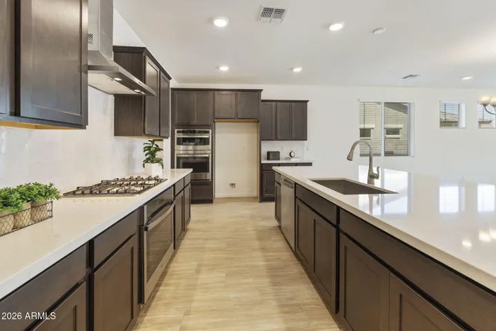 GOURMET KITCHEN WITH BUILT-IN APPLIANCES, STAGGERED CABINETS, QUARTZ COUNTERS AND A DESIGNER BACKSPLASH.