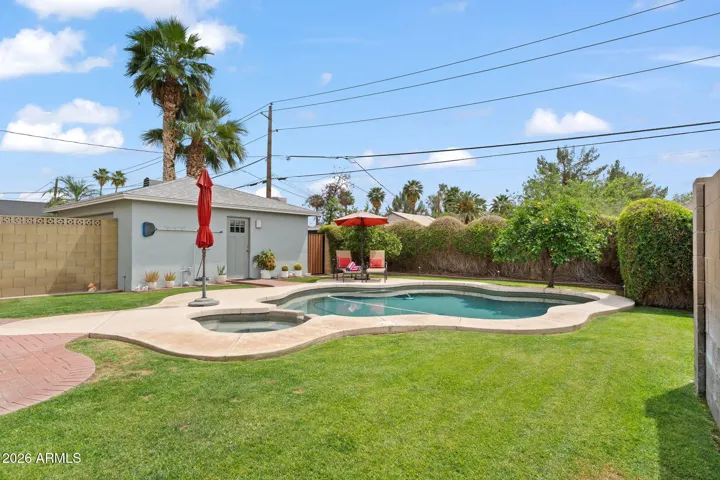 Lush yard with mature plants and a salt water pool and hot tub