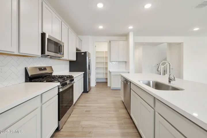PAINTED CABINETS, QUARTZ COUNTERS, DESIGNER BACKSPLASH, STAINLESS STEEL APPLIANCES AND LARGE WALK IN PANTRY
