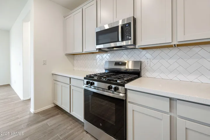 PAINTED CABINETS, QUARTZ COUNTERS, DESIGNER BACKSPLASH, STAINLESS STEEL APPLIANCES AND LARGE WALK IN PANTRY