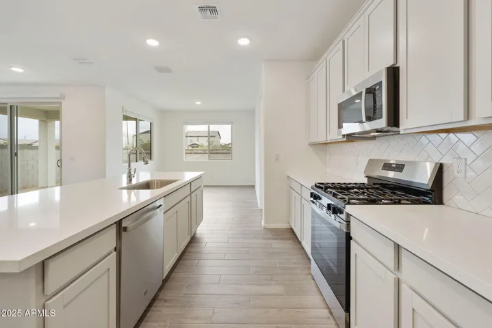 PAINTED CABINETS, QUARTZ COUNTERS, DESIGNER BACKSPLASH, STAINLESS STEEL APPLIANCES AND LARGE WALK IN PANTRY