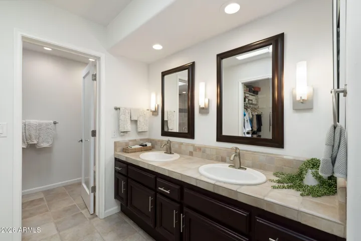 Updated Scottsdale bathroom with dual sinks, extensive vanity space, framed mirrors, modern lighting, and convenient access to the walk-in closet.