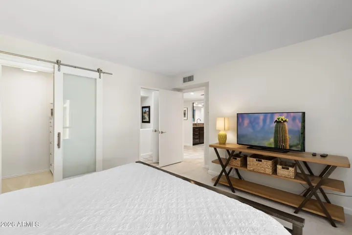 Generous secondary suite with modern sliding closet doors, neutral color palette, and direct access to the updated ensuite bathroom and walk-in closet.