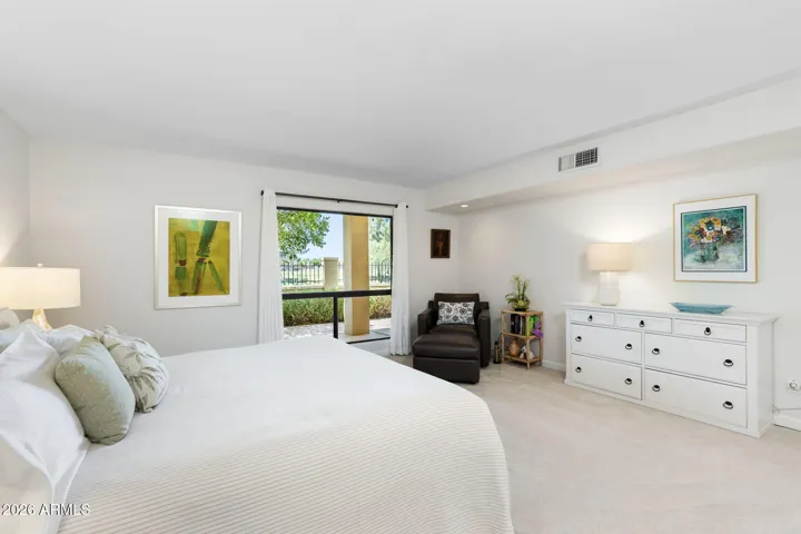 Spacious Scottsdale owner’s suite with large picture window, cozy sitting area, abundant natural light, and peaceful greenbelt views.