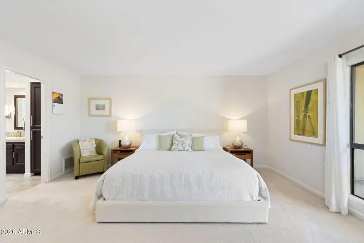 Expansive Scottsdale primary bedroom featuring plush carpeting, neutral finishes, oversized layout, and direct access to the ensuite bath for a relaxing retreat.