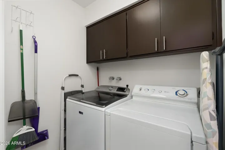 Spacious laundry area with upper storage cabinetry, full-size washer and dryer, and organized utility space designed for convenience and functionality.
