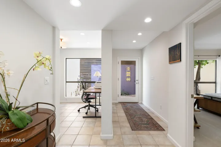 Welcoming Scottsdale entry hall featuring tile flooring, recessed lighting, modern glass front door, and a flexible workspace filled with natural light.