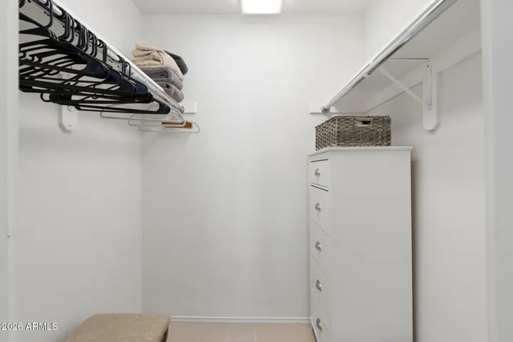 Description: Large walk-in closet with built-in organization, shelving, hanging space, and overhead lighting providing practical storage solutions in Scottsdale.