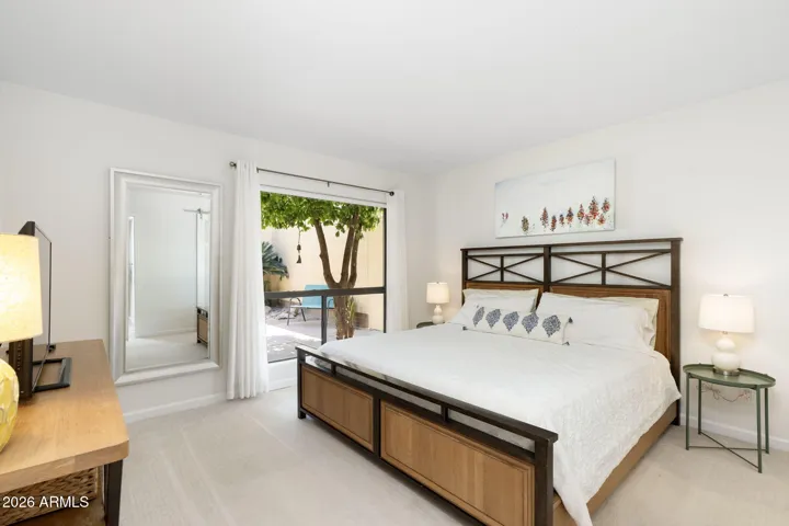 Comfortable Scottsdale secondary bedroom featuring plush carpeting, large picture window, peaceful outdoor views, and bright neutral finishes throughout.