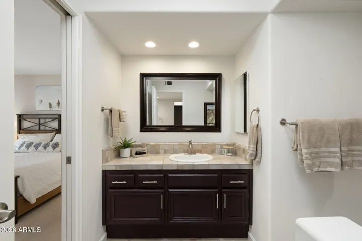 Well-appointed ensuite bathroom featuring an expansive vanity, framed mirror, updated lighting, and abundant cabinet storage for everyday comfort.