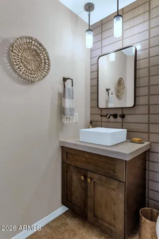 Updated cabinetry, decorative wall tile, vessel sink, floating shelves & linen closet