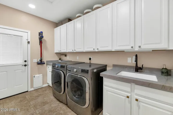 Abundant storage, quartzite countertops, separate exterior pedestrian door with awning, built-in drying rack, full-size laundry sink & washer & dryer.