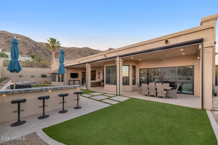Outdoor kitchen, faux grass and plenty of patio space with travertine tile.