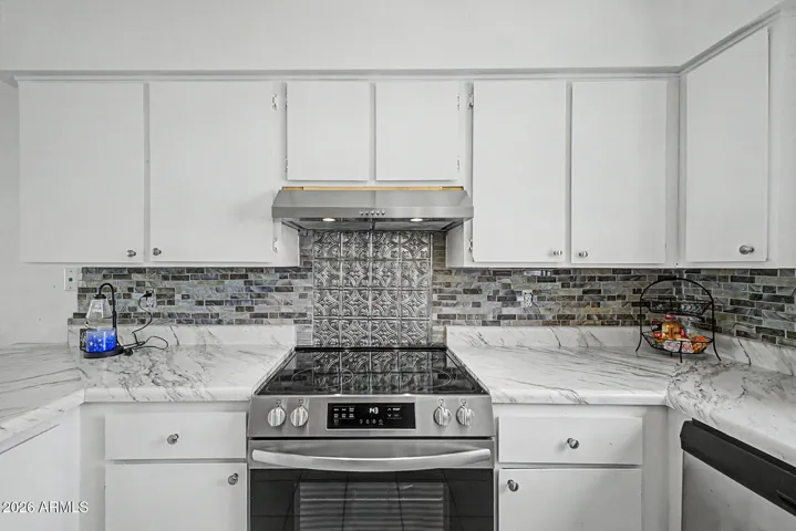 Bright white cabinetry complement white/gray backsplash and countertops.