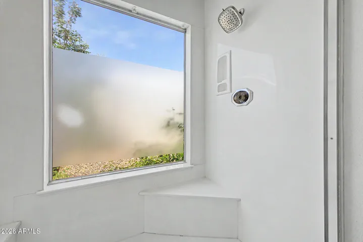 Huge Shower with shelving and large window has been obscured for privacy.