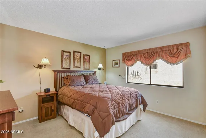 The generous primary bedroom suite features soft carpeting, a ceiling fan, and a peaceful layout with a private entrance to the attached bath.