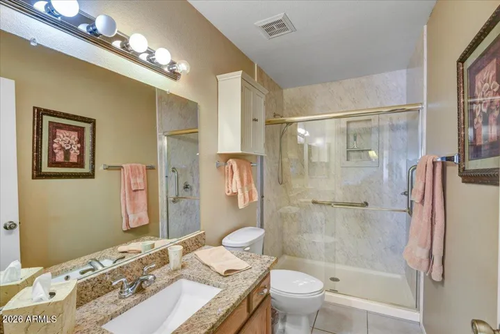 The primary ensuite bathroom includes a spacious vanity with granite countertops, bright lighting, and a walk-in shower