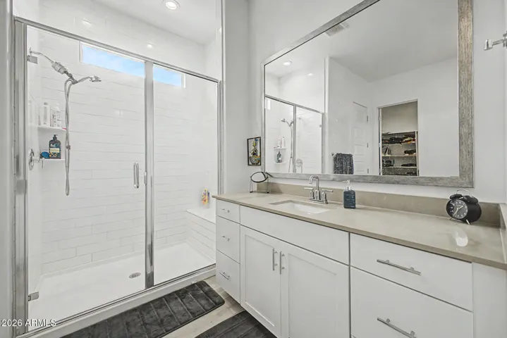 Primary bathroom w/ walk in shower, natural light, white cabinetry