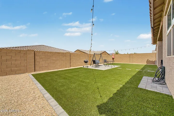 Main backyard with turf, covered patio and paved seating area