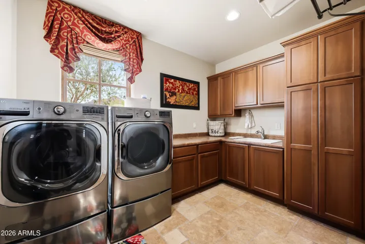 Functional laundry room with abundant cabinetry, extra storage, and a utility sink.