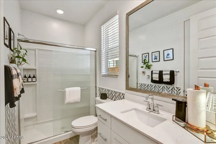 This clean and modern bathroom features a white vanity with ample cabinet storage, a large mirror, and updated lighting. The neutral tones and functional design make it a great addition to the home's layout.