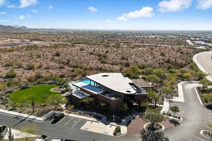 An expansive overhead view of the pristine community facility at Mystic at Lake Pleasant, showcasing the large swimming pool layout, ample poolside lounging space, and beautifully maintained desert landscaping designed for luxury everyday living.