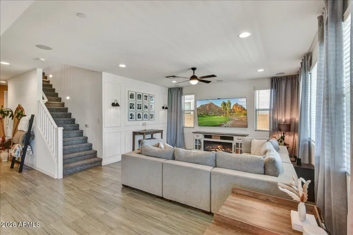 The expansive open-concept family room features high ceilings, contemporary wood-look flooring, and a staircase leading upstairs. This spacious footprint easily accommodates large-scale seating arrangements and connects seamlessly to the dining and kitchen areas.