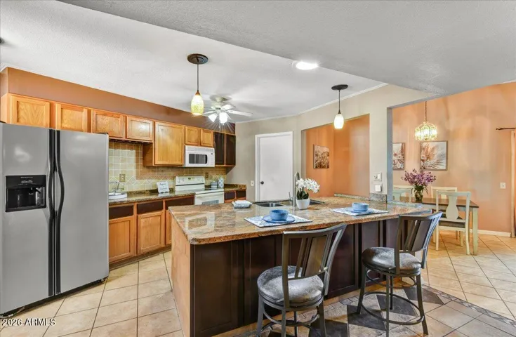Spacious and bright kitchen complete with ample cabinetry, modern stainless steel appliances, a generous island with breakfast bar seating, and warm recessed lighting.