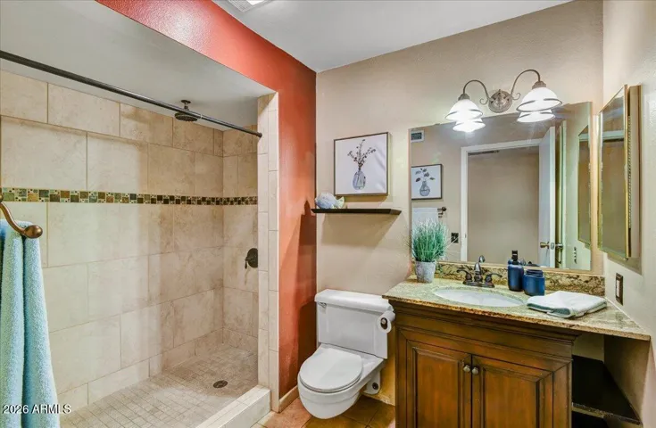 Clean and well-maintained full bathroom featuring a tile shower and a spacious vanity with granite counters.
