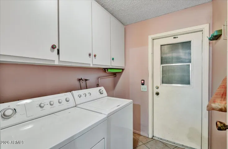 Dedicated indoor laundry room equipped with upper storage cabinets and direct exterior/garage access for added convenience.