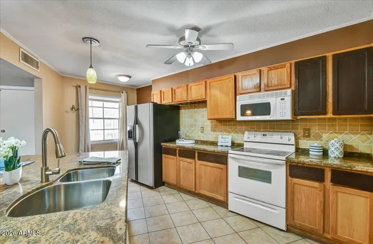 Alternate view of the kitchen highlighting the functional layout, expansive countertop workspace, built-in microwave, and seamless flow into the living areas.