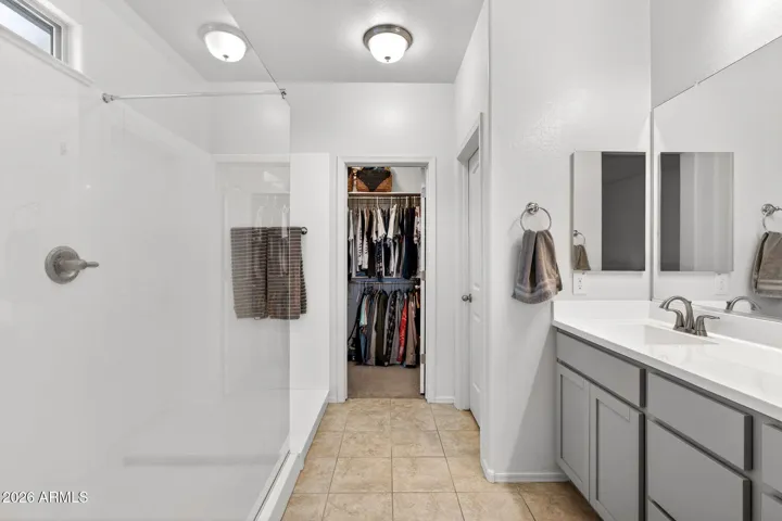 Primary bathroom with large walk in shower, double sinks, toilet room, walk in closet
