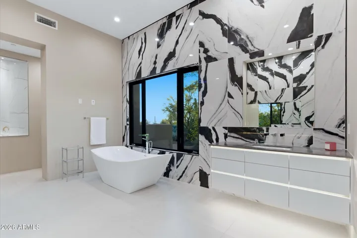 Showcases a contemporary design with a statement soaking tub, and elegant custom cabinetry topped with premium stone surfaces.”