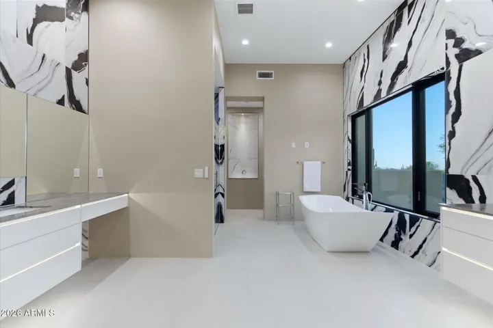 “A spa-inspired primary bath designed for ultimate relaxation, featuring a sleek freestanding soaking tub, an expansive walk-in glass shower, and dual vanities with designer finishes.”