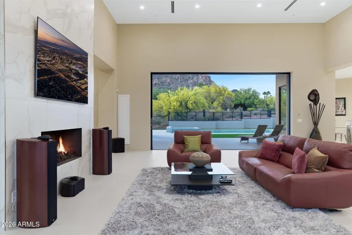 The Great Room features soaring ceilings, dramatic gas fireplace, and 18 Foot Automated Wall of Disappearing Glass that opens up the space to the Rear Patio and Outdoor Entertaining Area.