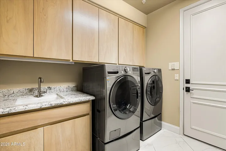 This laundry room has it all, upper and lower cabinetry, a utility sink, and a hanging/drying rod.