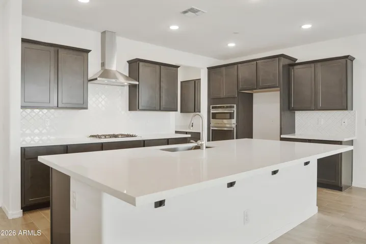 GOURMET KITCHEN WITH BUILT IN APPLINACES. DESIGNER BACKSPLASH, DESIGNER HOOD, GAS COOKTOP AND QUARTZ COUNTERS.