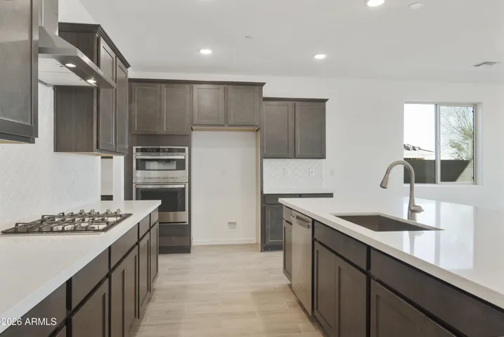 GOURMET KITCHEN WITH BUILT IN APPLINACES. DESIGNER BACKSPLASH, DESIGNER HOOD, GAS COOKTOP AND QUARTZ COUNTERS.