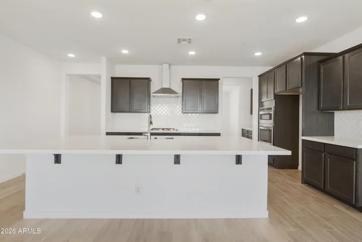 GOURMET KITCHEN WITH BUILT IN APPLINACES. DESIGNER BACKSPLASH, DESIGNER HOOD, GAS COOKTOP AND QUARTZ COUNTERS.