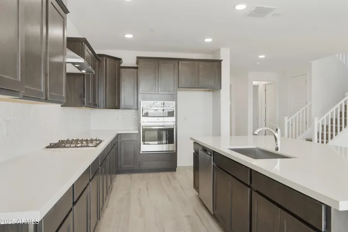 GOURMET KITCHEN WITH GAS COOKTOP, OVEN MICROWAVE COMBO OVEN, DESIGNER HOOD AND UPGRADED CABINETS, COUNTERS AND BACKSPLASHES.