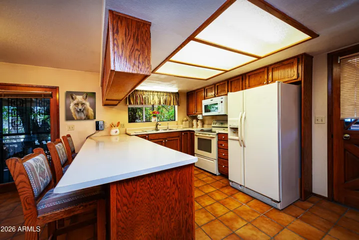 Kitchen with counter seating. tiled flooring, exit to side yard.