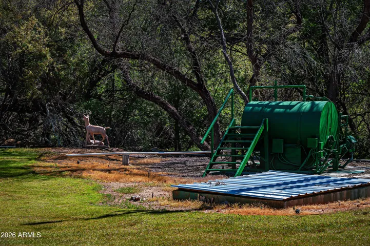 This tank fills quickly from the 2 wells and irrigates the grassy property. Blue lid covers valve system.