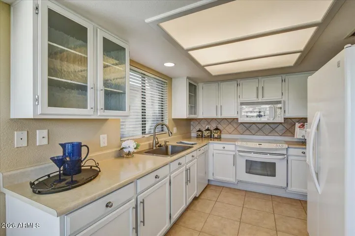 kitchen features white cabinets and appliances.