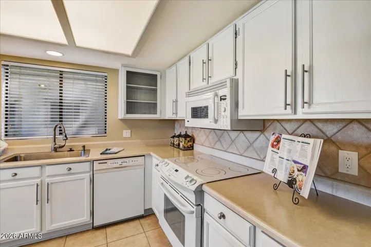kitchen features white cabinets and appliances.